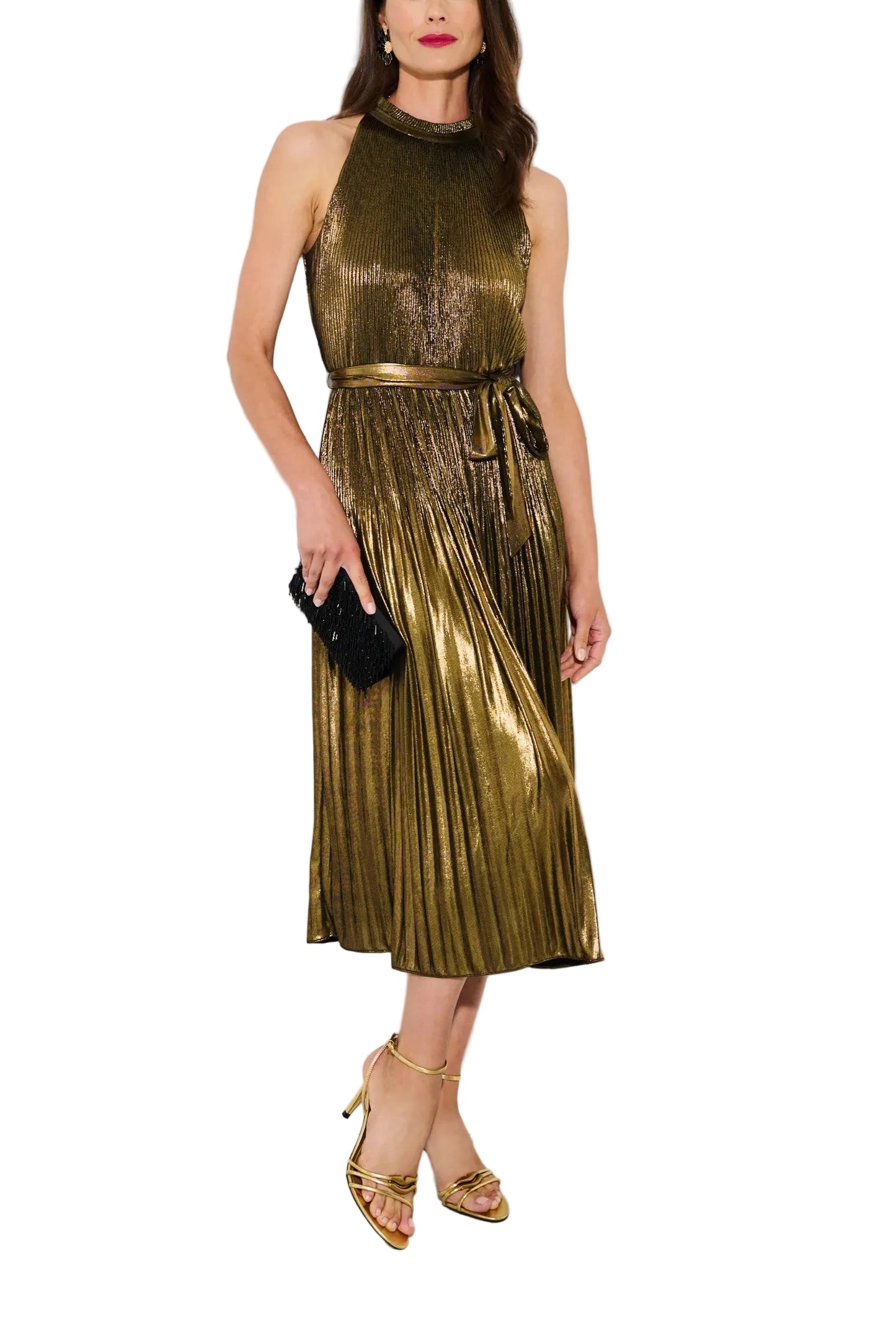 Woman wearing a gold pleated dress against a white paneled wall.
