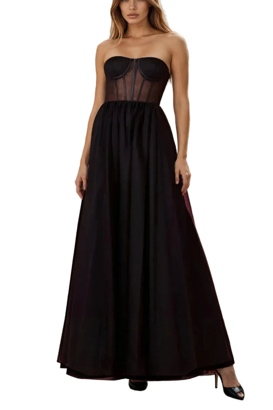 Woman in a black dress standing on a balcony with a cityscape in the background