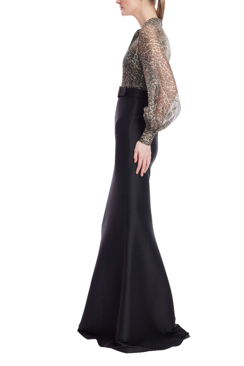 Woman wearing a black evening gown with a sheer embellished top on a white background