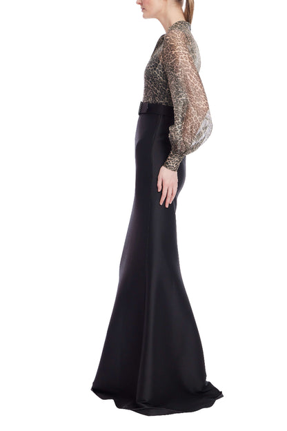 Woman wearing a black evening gown with a sheer embellished top on a white background