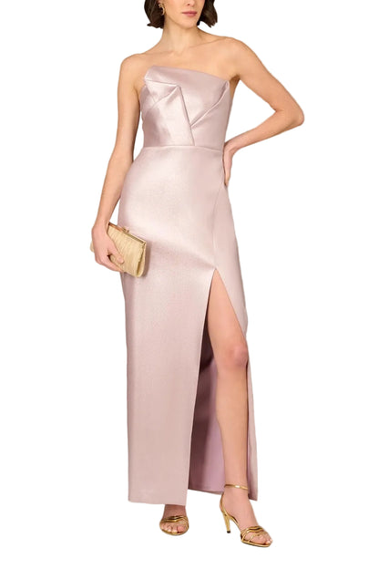 Woman wearing a strapless pink gown with a slit on a plain background